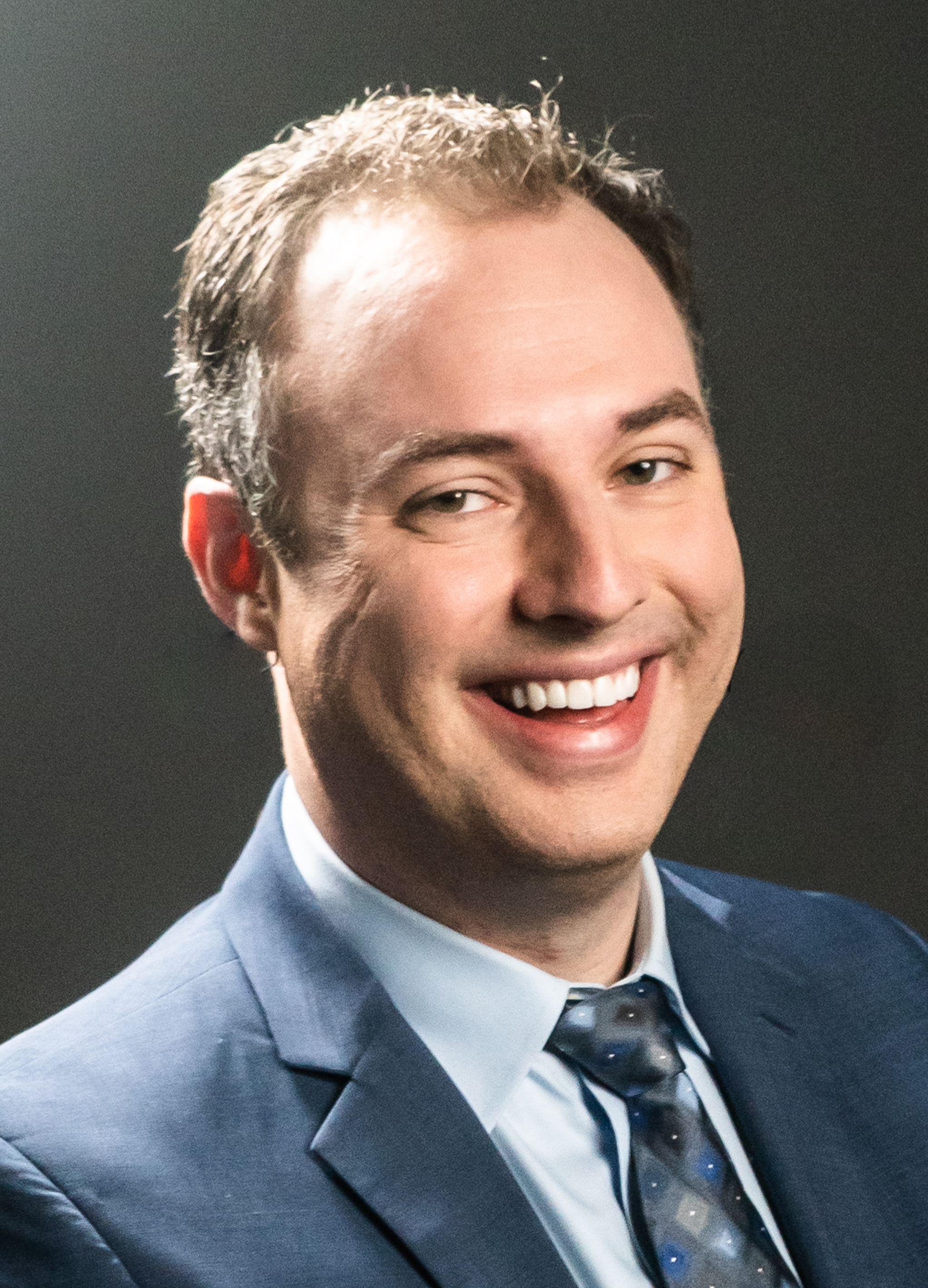 Day9 wearing a blue suit and tie, smiling at the camera